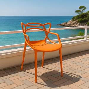 Orange bistro plastic chair with artistic backrest placed on a coastal patio overlooking the ocean.