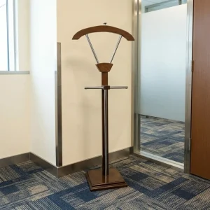 Executive valet stand featuring a contoured dark wood coat hanger, polished chrome support bars, a horizontal pants rod, and a weighted square wooden base.