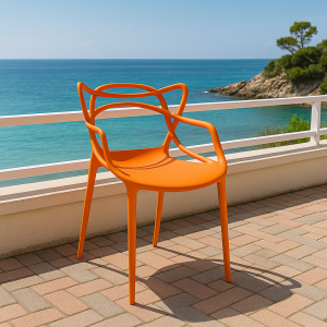 Orange bistro plastic chair with artistic backrest placed on a coastal patio overlooking the ocean.