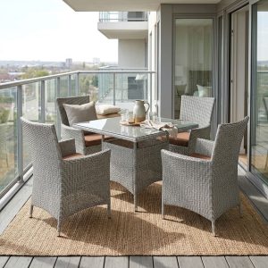 Outdoor Rattan Dining Set with four light gray woven armchairs, brown seat cushions, high backrests and a rectangular dark glass-top table.