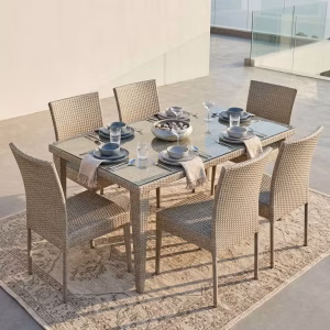A 6 Seater Rattan Outdoor Dining Set featuring a rectangular table with a transparent tempered glass top and six matching woven light grey wicker chairs.