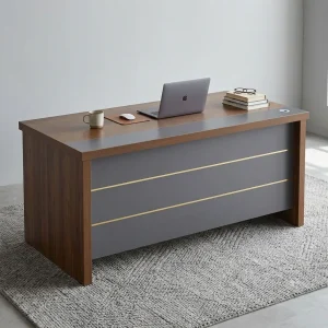 A premium executive desk set featuring a walnut-finish wood desk with a thick rectangular top, an integrated matte gray modesty panel accented by three horizontal gold brass lines, and a standalone three-drawer rolling wooden filing cabinet with a key lock on the top drawer.