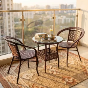 A premium 2-Seater Rattan Bistro Set featuring two deep brown hand-woven synthetic rattan tub armchairs with detailed weave patterns, paired with a matching round woven bistro table topped with clear tempered glass and an integrated lower storage shelf.