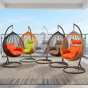 A collection of five teardrop-shaped Rattan Swing Hammock Chair units featuring hand-woven synthetic wicker baskets suspended from curved iron arch frames on circular pedestal bases, showcasing varied color ways including black with orange cushions, orange with lime green cushions, white with gray cushions, dark brown with plaid cushions, and natural tan with orange cushions.